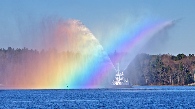 A tugboat spraying colored water streams