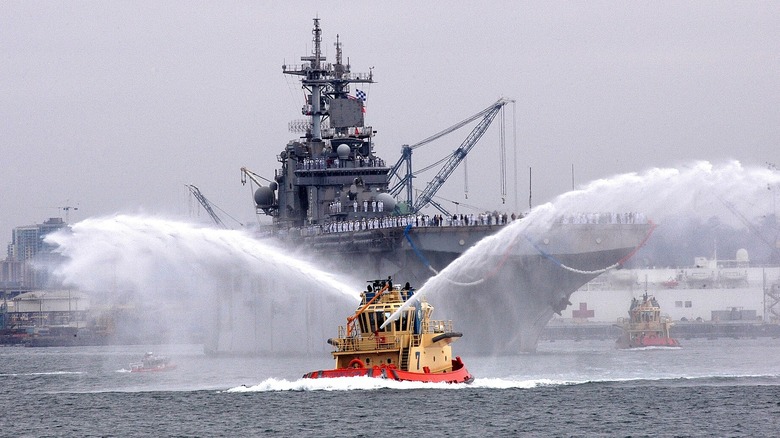 A tug boat spraying water in celebration of the arrival of a ship