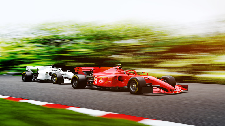 A red Porsche racing ahead of a white car in Formula 1