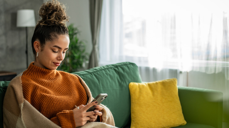 woman using iphone on couch