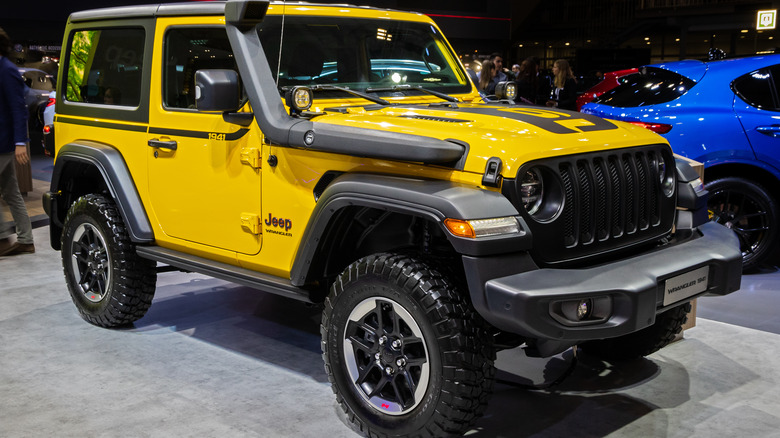 A yellow Jeep Wrangler on display at a car show.