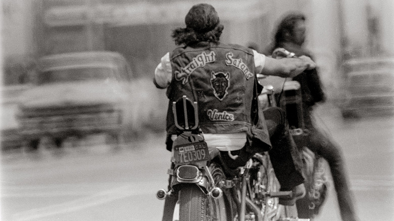 A biker with "Straight Satans Venice" on the back of his cut, riding his motorcycle