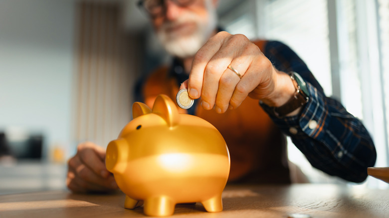 man putting coin in piggy bank