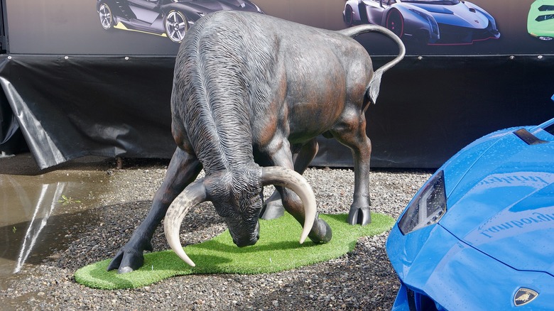 Lamborghini Bull statue next to a Lamborghini car