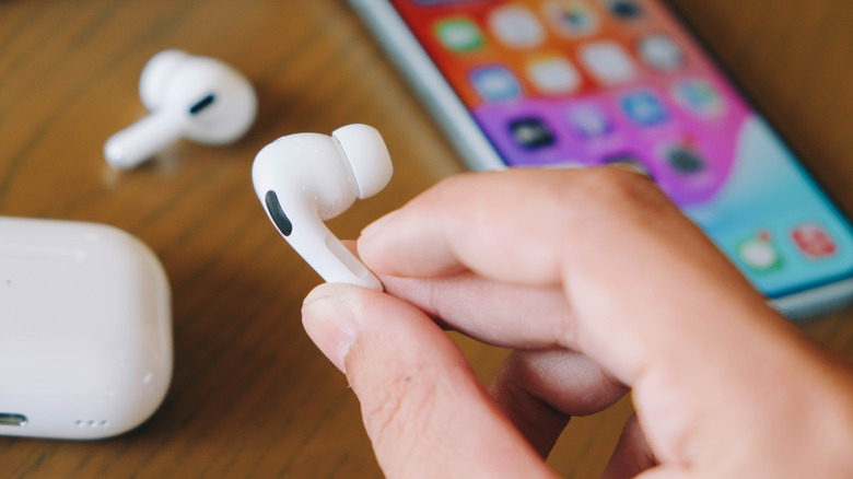 Person holding one AirPod in their hand