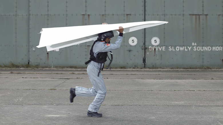 Man running with large paper airplane