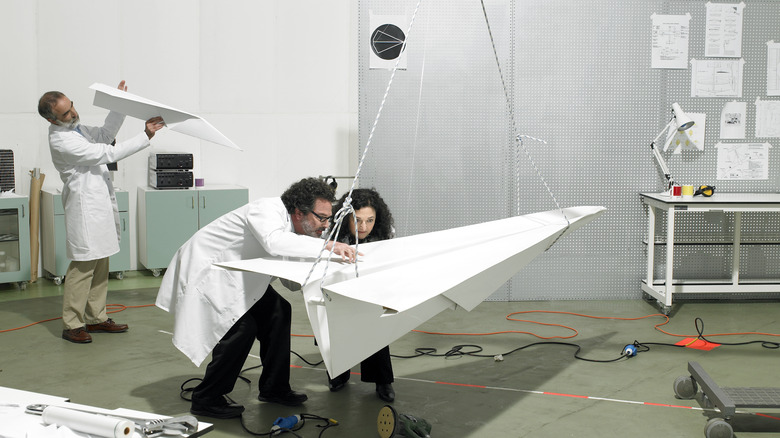 Scientists with large paper airplane