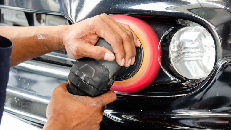 Person polishing auto headlights with tool