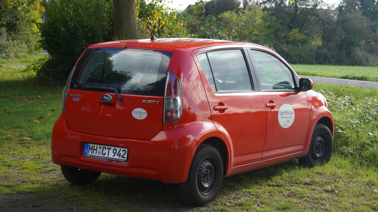 A red fourth-generation Subaru Justy parked on the grass