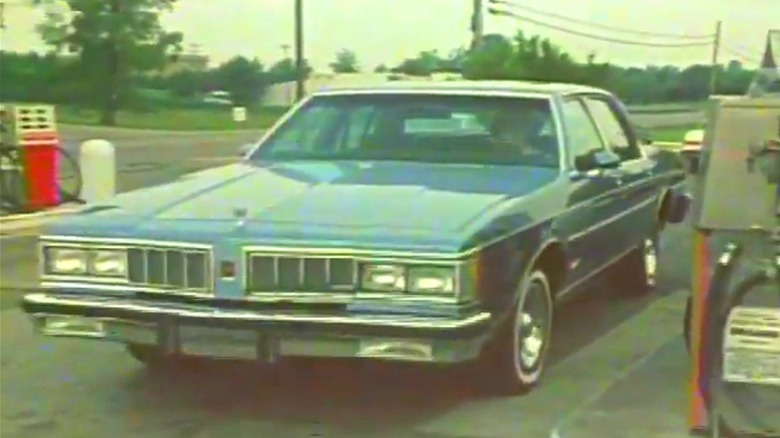 A 1980 Oldsmobile Diesel pulling up to the pump in a classic dealer film.