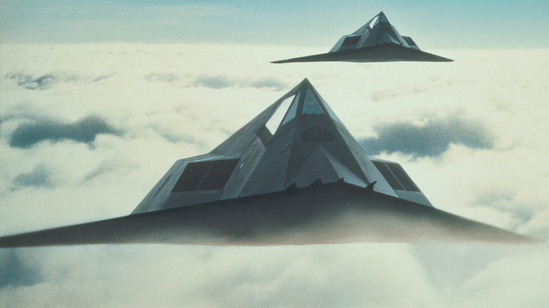 Rendering of two F-117 Nighthawks flying in close formation as they rise above clouds