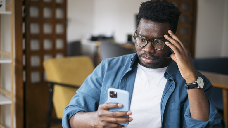 Person looking upset at smartphone