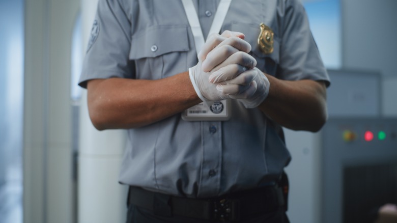 A TSA agent wearing gloves.