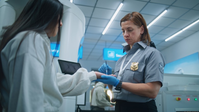 A TSA agent performs a swab test on a passenger.