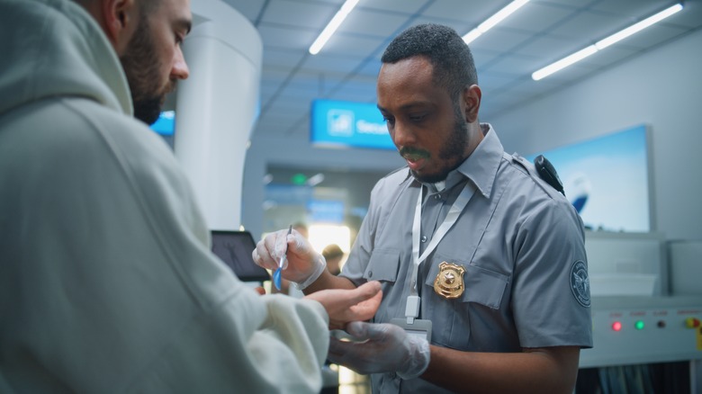 A TSA agent performs a swab test on a passenger.