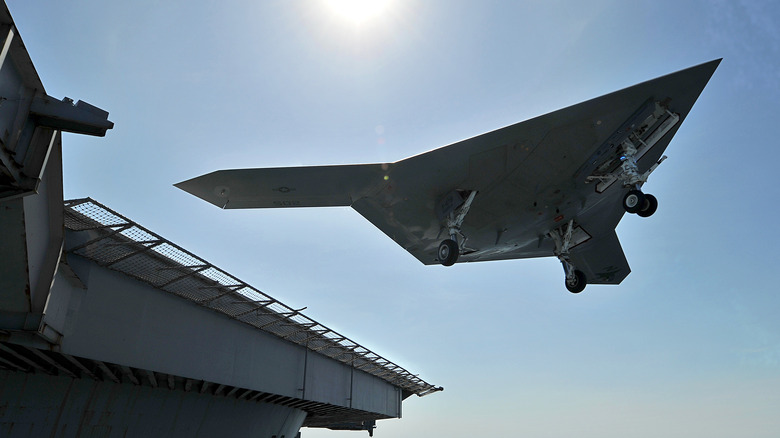 X-47B flying above aircraft carrier