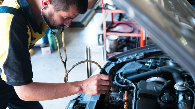 Mechanic listening to a car engine