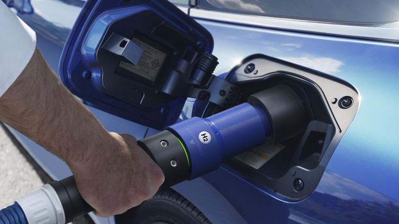 Man's arm inserting hydrogen fueling nozzle into Toyota Mirai