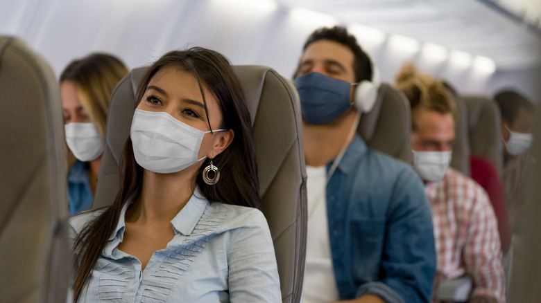 A group of passengers sport masks while riding a flight during the COVID-19 pandemic