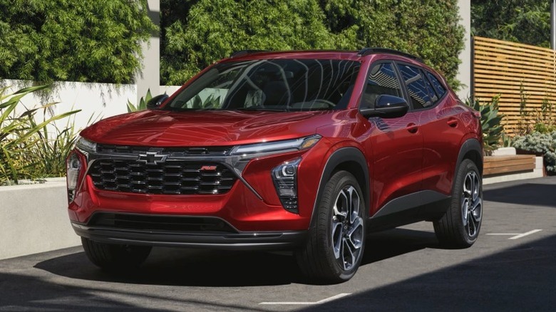 3/4 shot of a red Chevrolet Trax parked on a paved surface next to a white fence