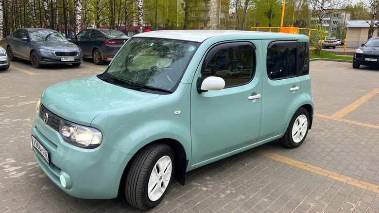 A green Nissan Cube snapped in a parking lot