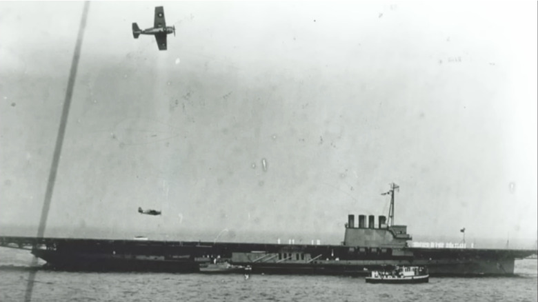 Plane flying over an aircraft carrier