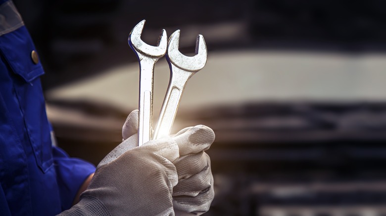 mechanic holding wrenches