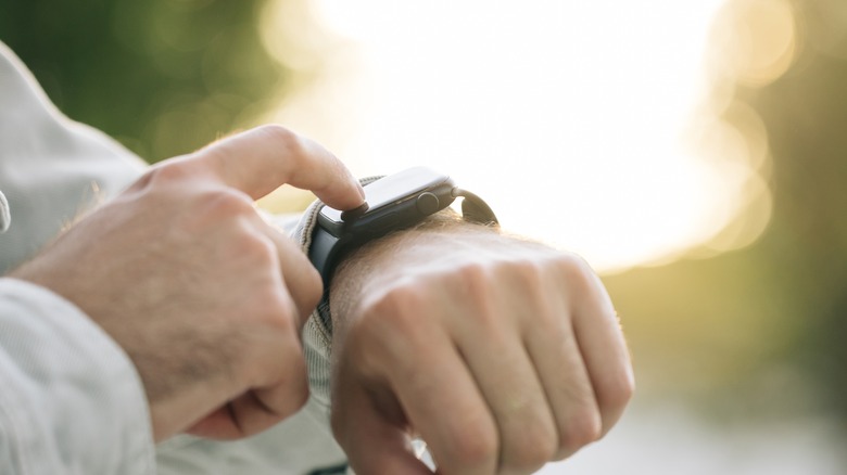 hand touching Apple Watch on wrist