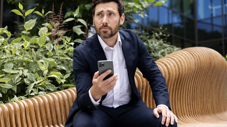 man unhappily using iphone