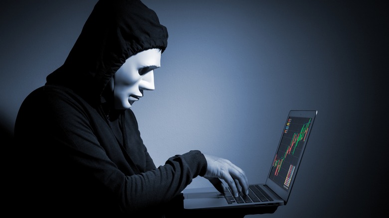 Masked scammer on laptop