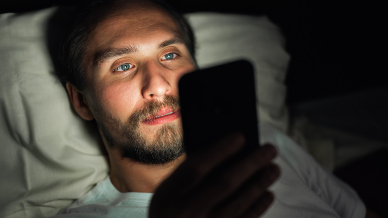 man with phone in bed