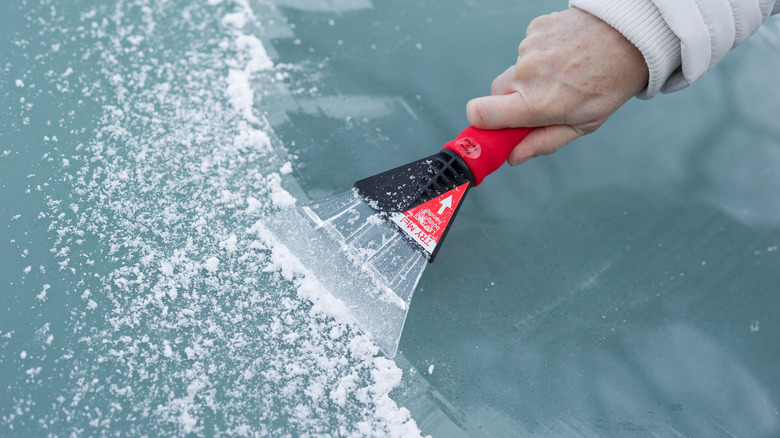 Person scraping ice off windshield