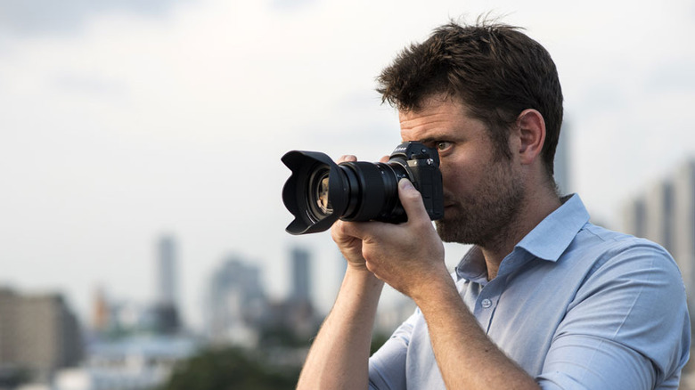 A photographer holds the Nikon Z mount 24-70mm lens on a camera