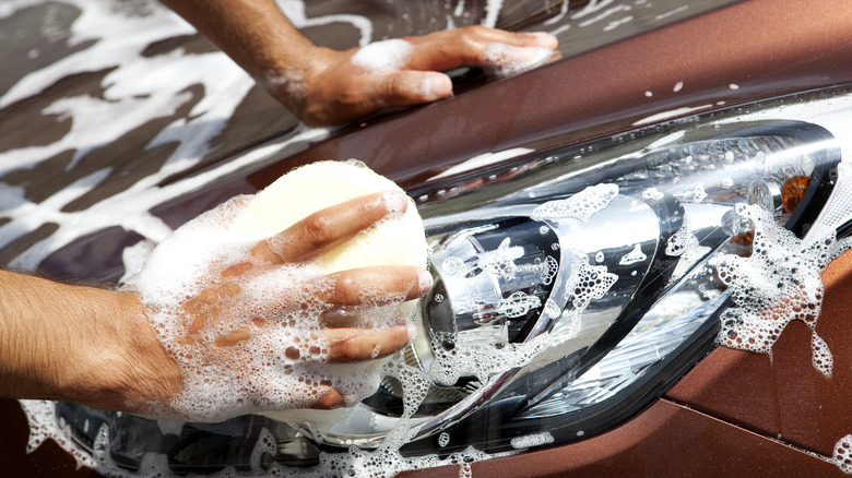man cleaning car headlights