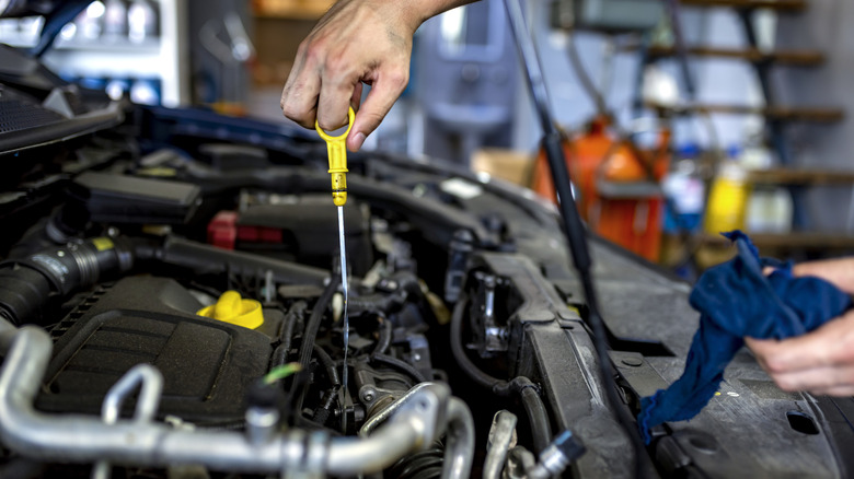 A car mechanic checking the oil level in a garage.