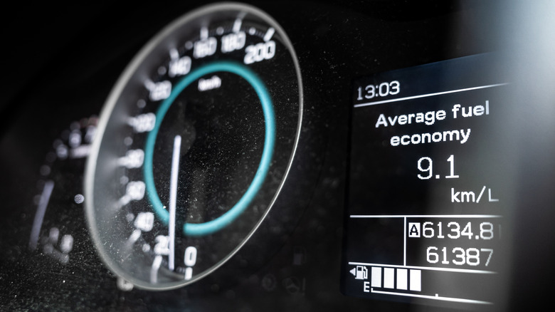 A fuel guage on empty with the average fuel consumption of a car displayed on the car's dashboard