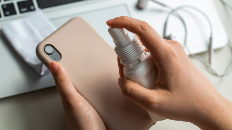 Person cleaning phone case with spray cleaner