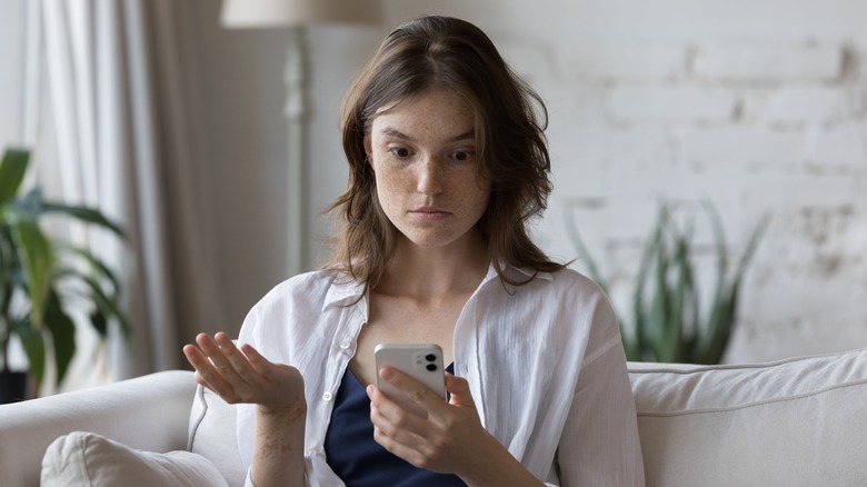 A woman looking shocked while staring at her iPhone screen