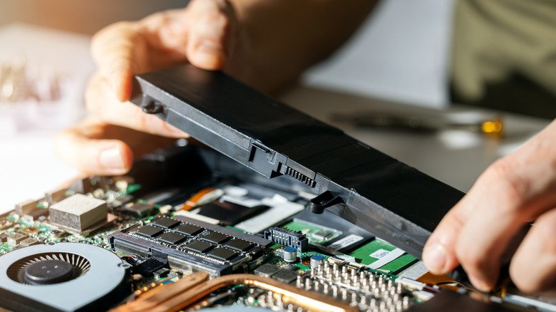 Man removing a laptop battery from the laptop