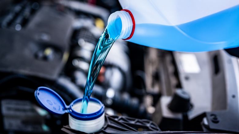 Pouring antifreeze fluid into windshield wiper tank