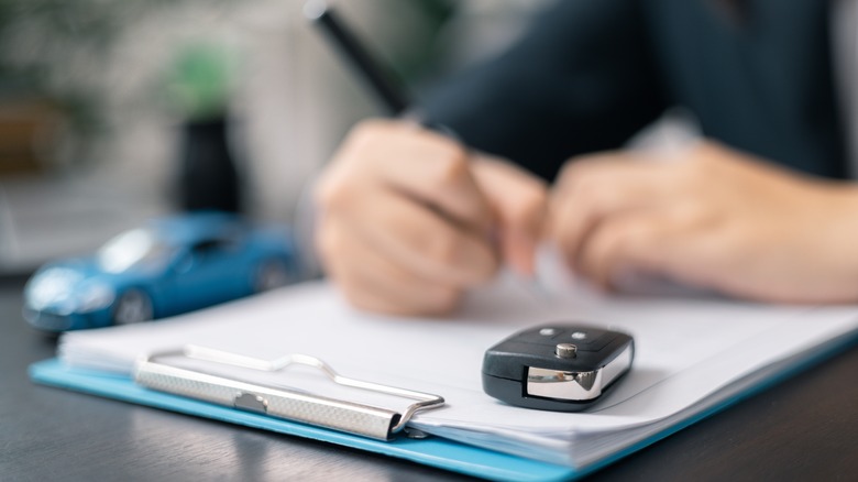 A person signing documents to get a new car.