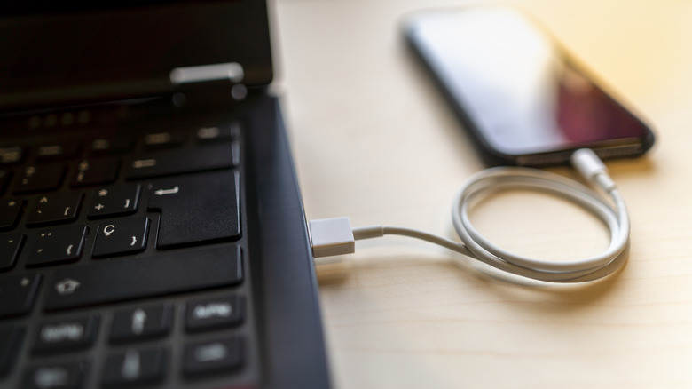 laptop charging iPhone on table