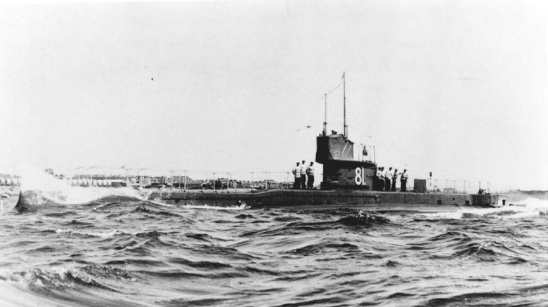 The HMS E1 underway on the surface with sailors standing on the hull