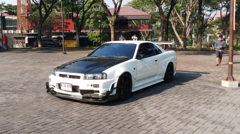 A white modified R34 Nissan Skyline GT-R, front 3/4 view