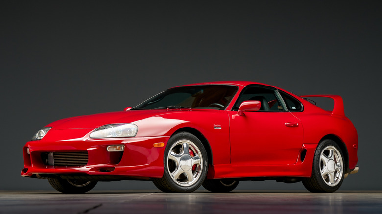 A Mk4 Toyota Supra in red, modified front bumper, front 3/4 view