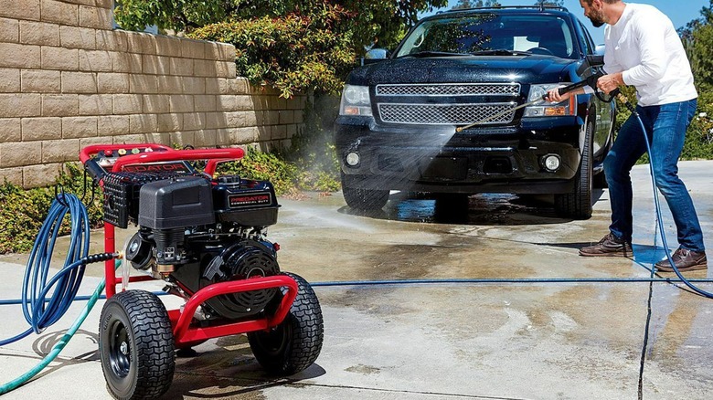 Man pressure washing car