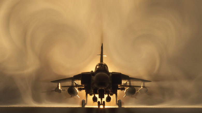 A fighter jet with air plumes behind it