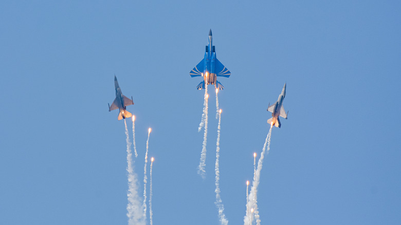 three fighter jets releasing flares in a flight display