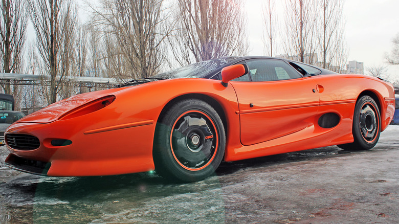 Orange Jaguar XJ220 parked in black room