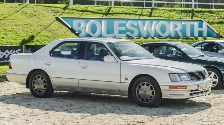 A two-tone white and silver Lexus LS400 on gravel, front 3/4 view